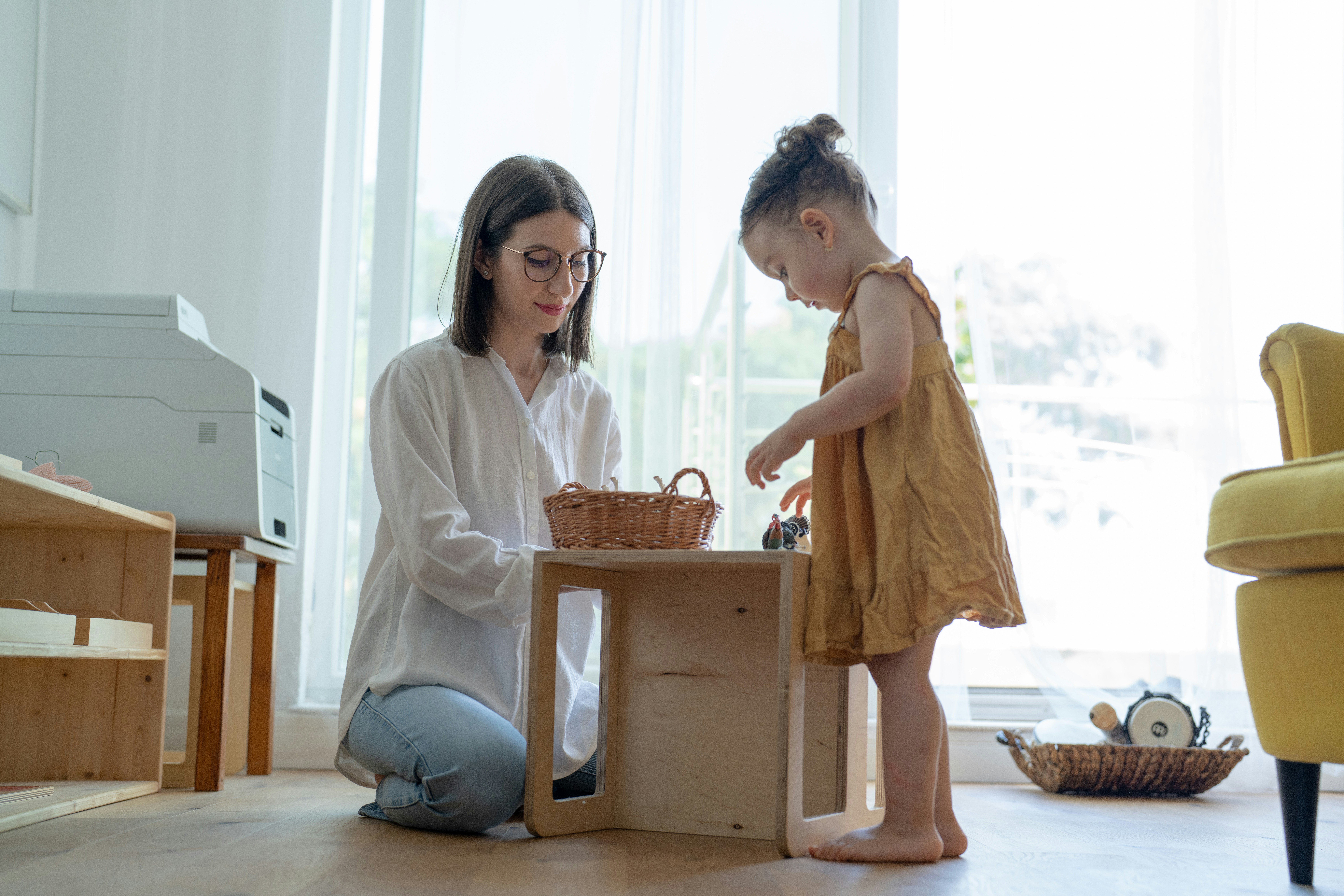 a play therapist plays watches a toddler girl play with toys on a small table in a new jersey play therapy session