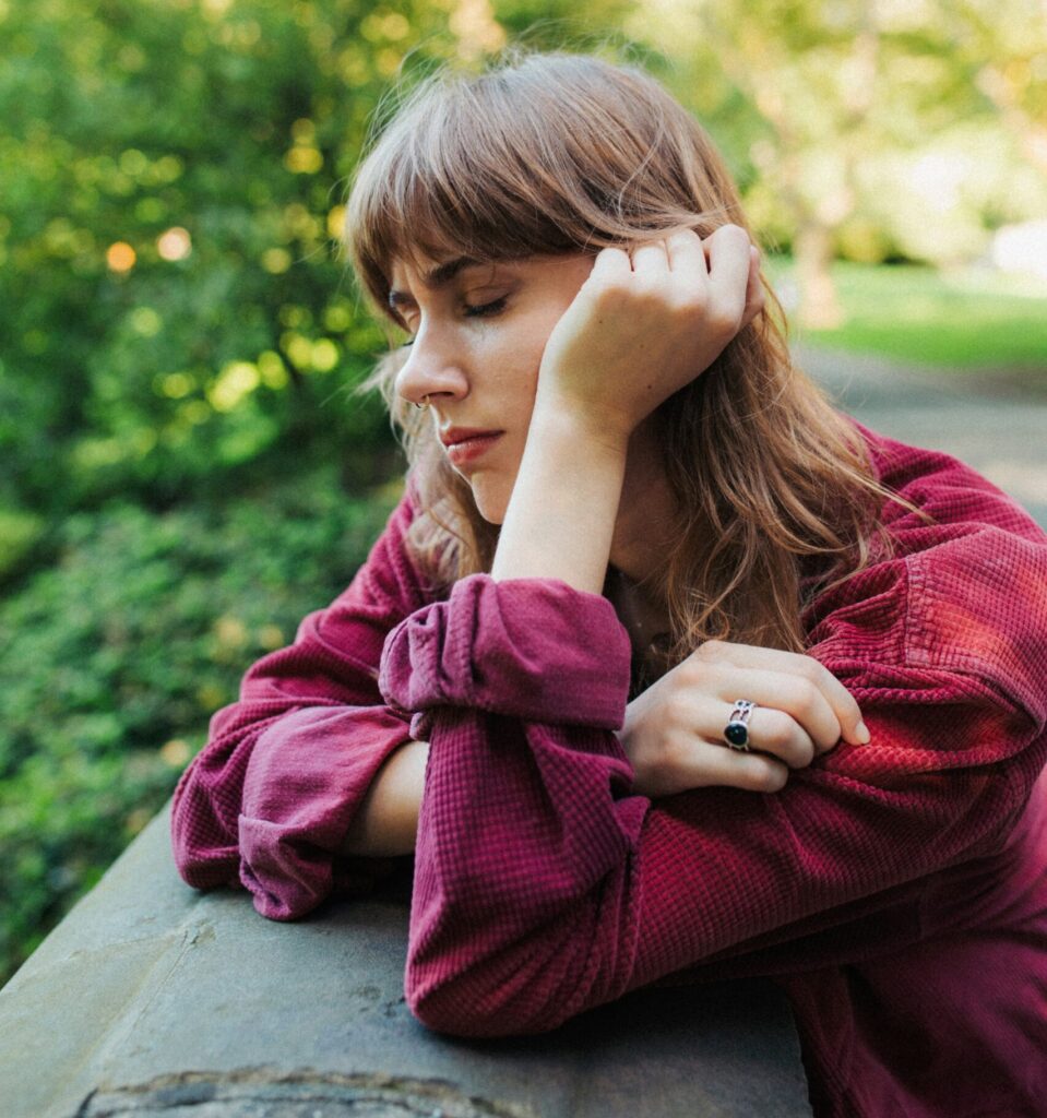 A woman looks sad as she grieves after losing a pet. She knows that the social stigma around pet loss is making it harder for her to grieve properly.