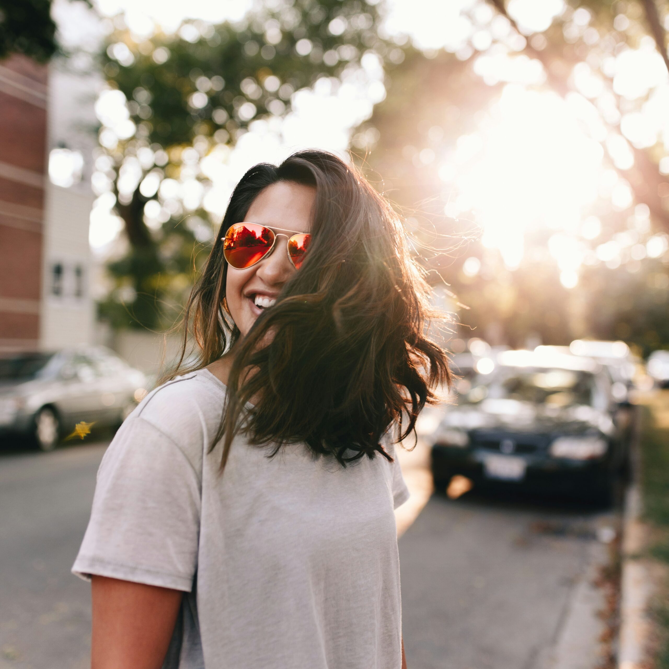 woman smiling as she crosses the street in the sunshine after beginning therapy