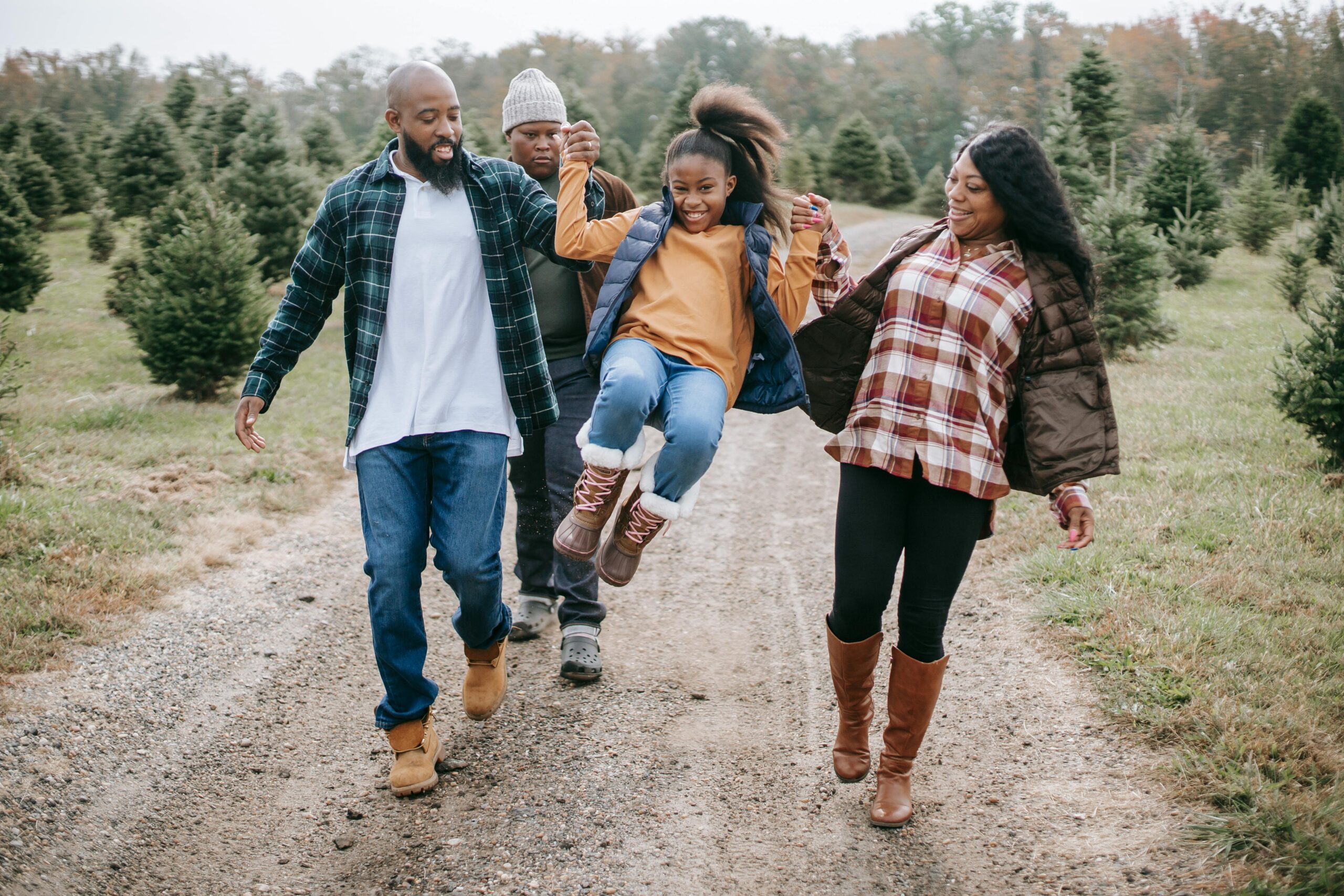 An African American family, two parents and two teenagers in a field of evergreen trees