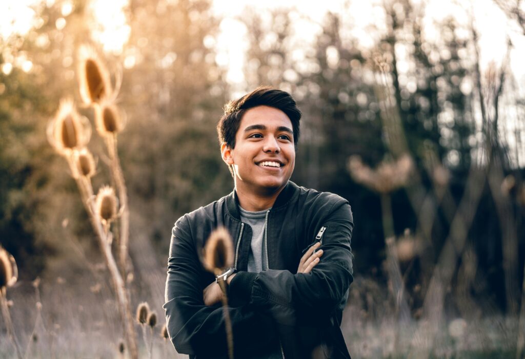 man sitting in a field of long grass smiling after setting boundaries