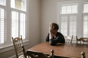 man with head in hand experiencing the impacts of trauma