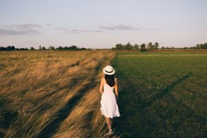 woman walking along fields representing grass is greener syndrome